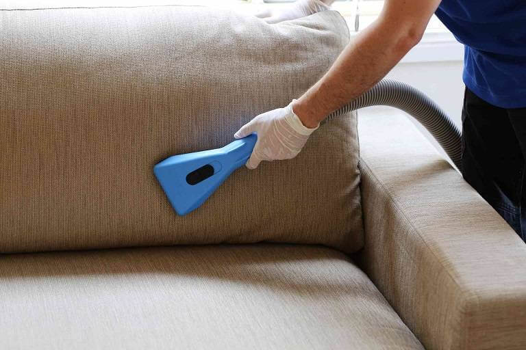 Mighty Clean professional with white gloves cleaning sofa